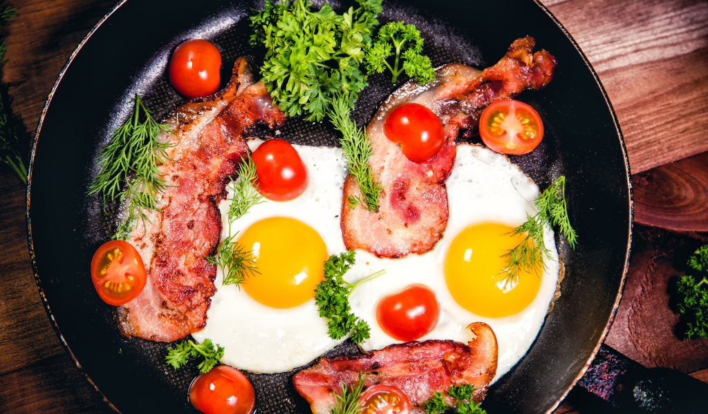 Яичница с беконом, помидорами и зеленью в сковороде на завтрак