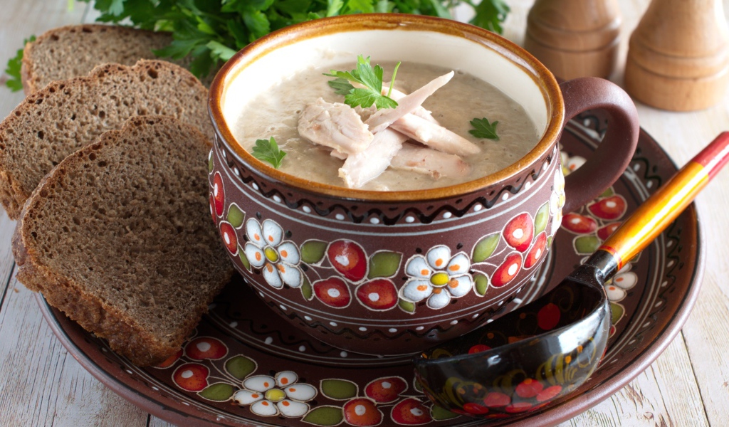 Суп с курицей в красивой тарелке на столе с черным хлебом