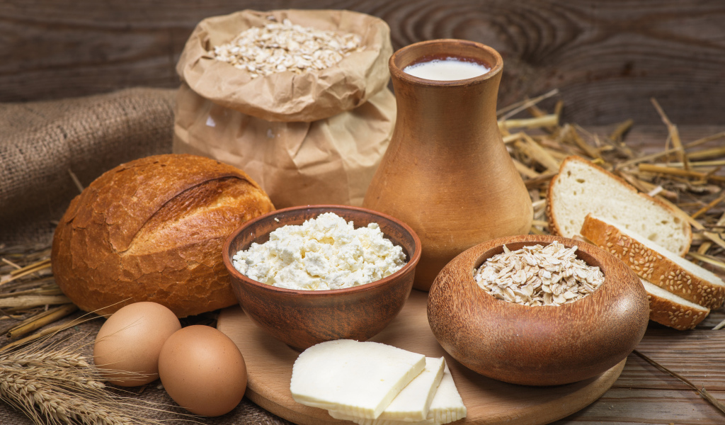 Натюрморт сыр, хлеб, яйца и молоко на столе 