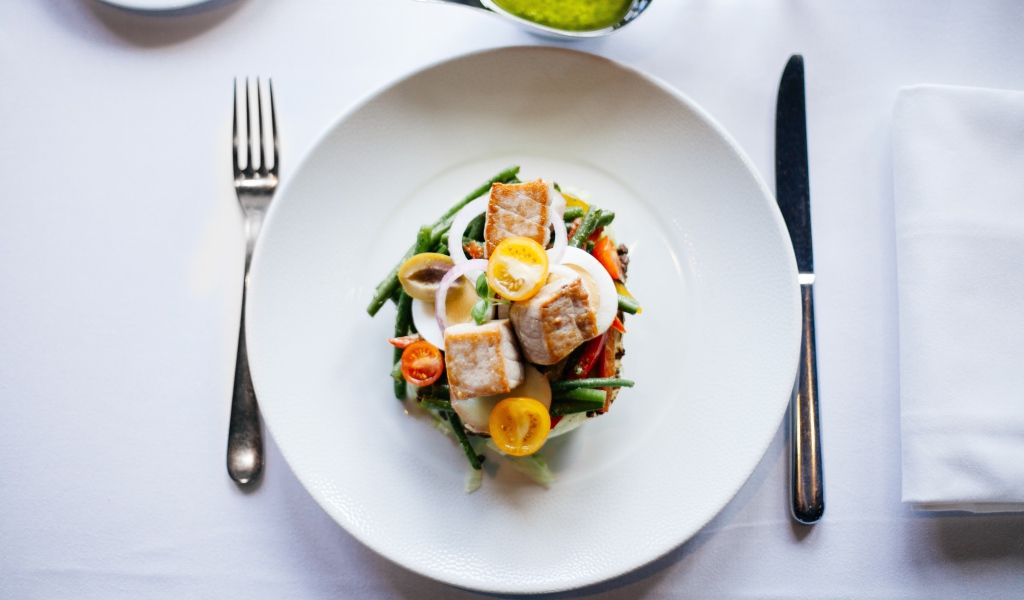 Овощной салат на белой тарелке со столовыми приборами