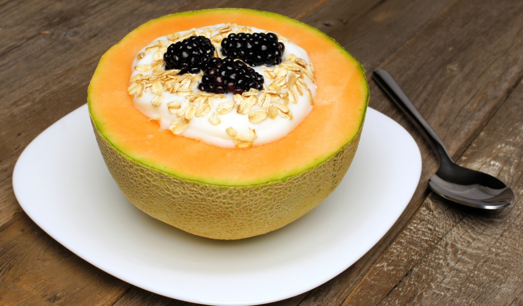 Йогурт с ежевикой и овсянкой в тарелке из свежей дыни на завтрак