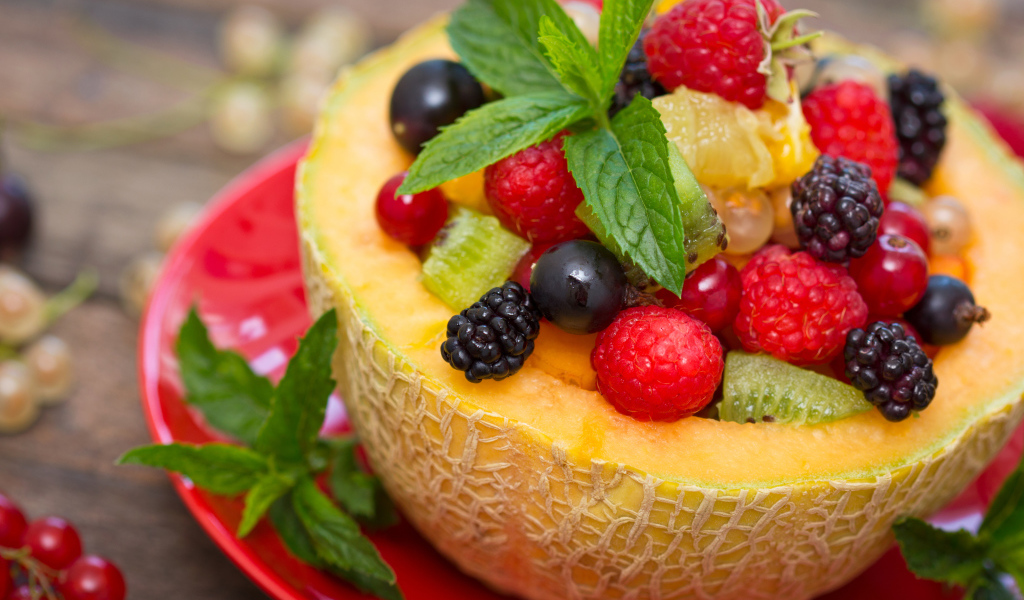 Аппетитные свежие ягоды с листьями мяты в половине дыни