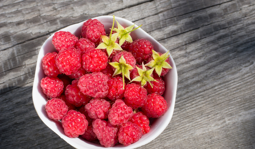 Аппетитная сочная свежая малина в белой тарелке 