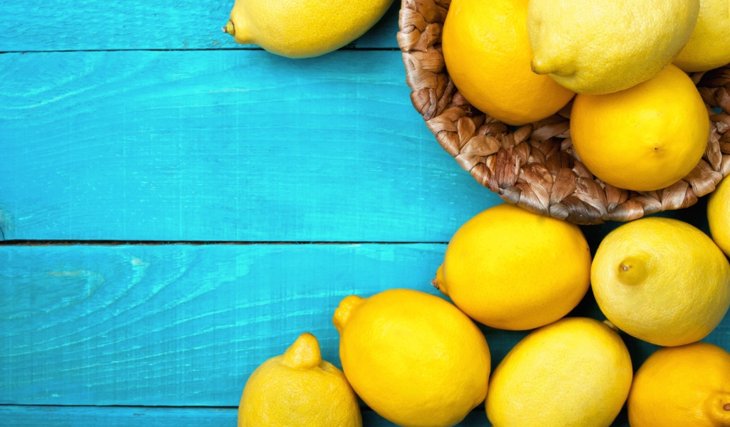 Свежие желтые лимоны лежат на голубой поверхности стола