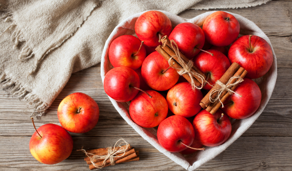 Красные яблоки в тарелке в форме сердца с корицей