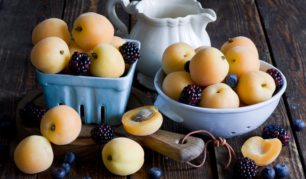 Спелые абрикосы и ягоды на столе 