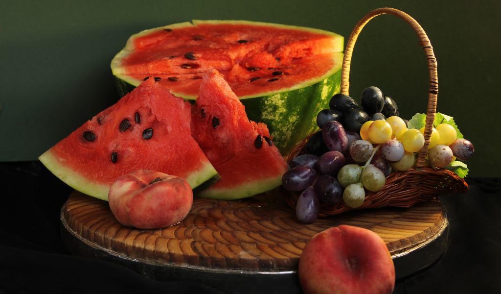 Нарезанный арбуз на столе с виноградом и персиками