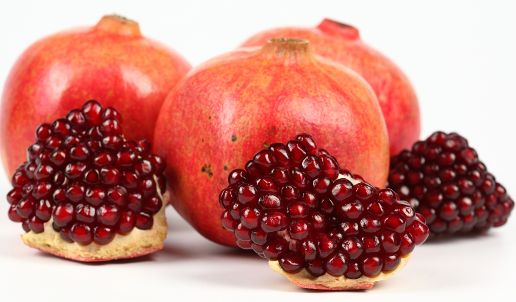 Три красных граната с ломтиками на белом фоне