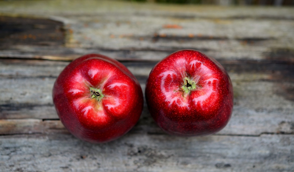 Два больших красных яблока на деревянном столе