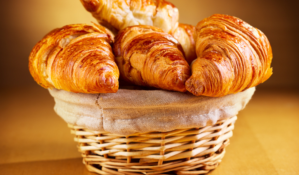 Корзина со свежими круассанами на столе