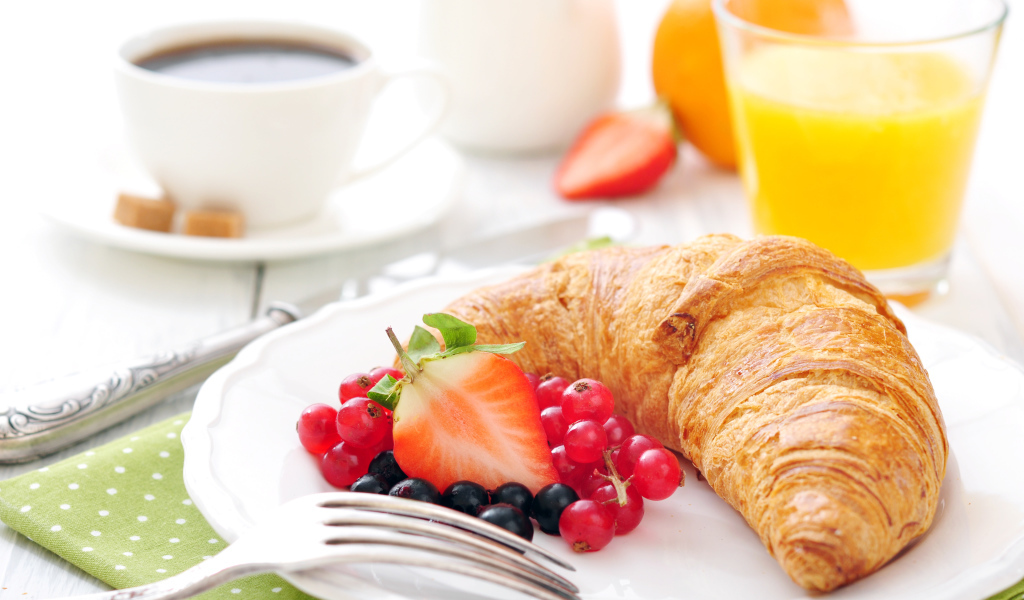 Свежий круассан на белой тарелке с ягодами 