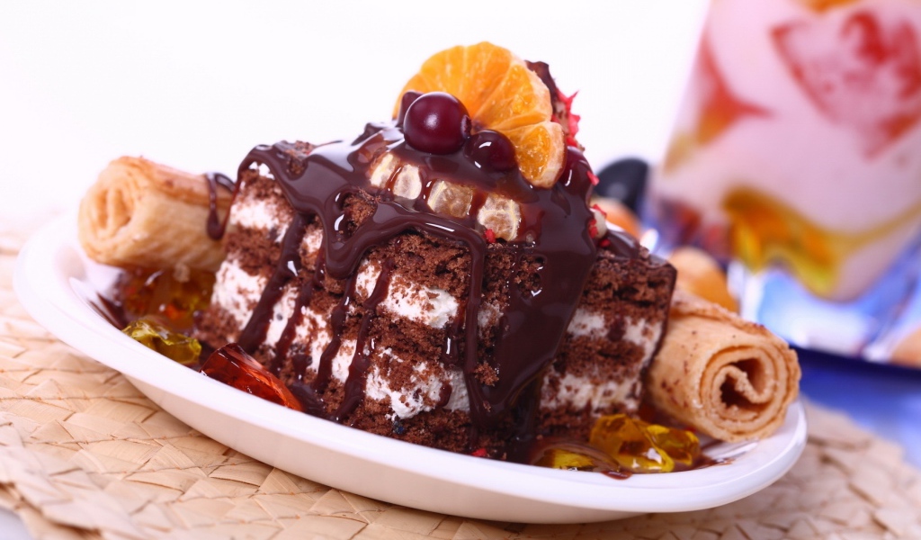 Аппетитное пирожное с шоколадной глазурью, трубочками и мандаринами