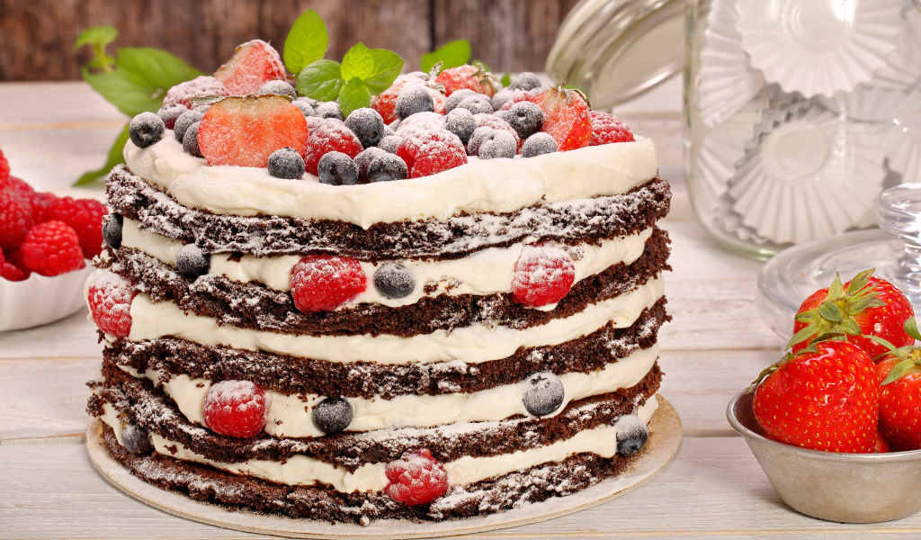 Аппетитный торт с кремом и ягодами посыпан сахарной пудрой