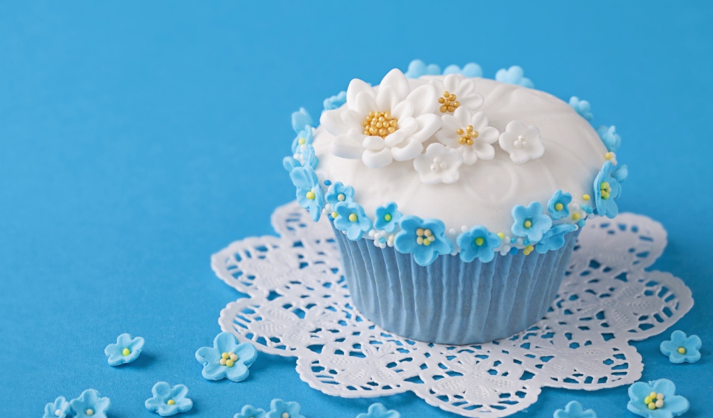 Аппетитный кекс украшен цветами на голубом фоне