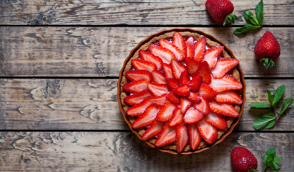 Аппетитный пирог со свежей клубникой на столе 