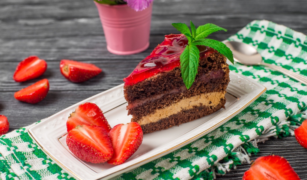 Аппетитный кусок торта на тарелке с ягодами клубники