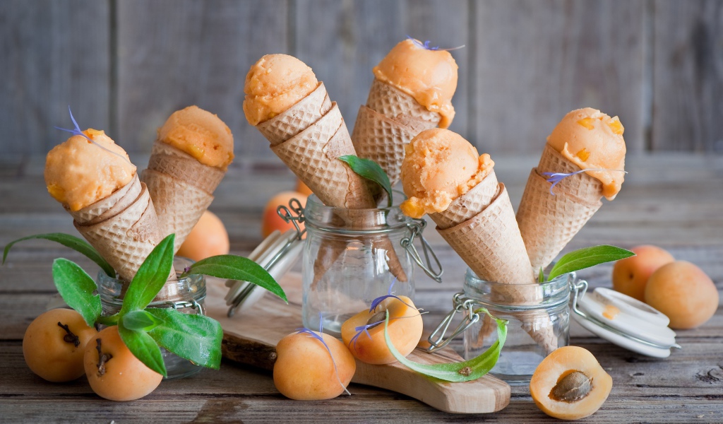 Абрикосовое мороженое в вафельных рожках со свежими фруктами на столе