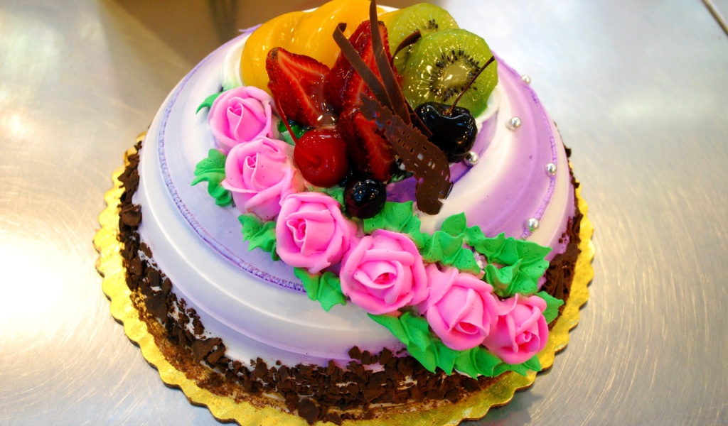 Красивый торт с фруктами украшен розовыми розами из крема