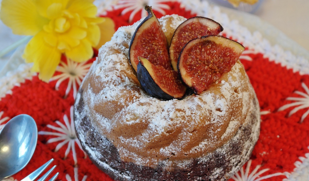 Кекс с инжиром и сахарной пудрой на столе с цветами
