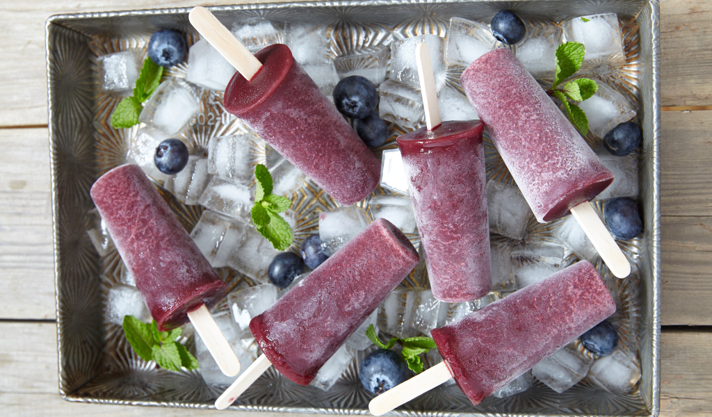Вкусное черничное мороженое на палочке в лотке со льдом