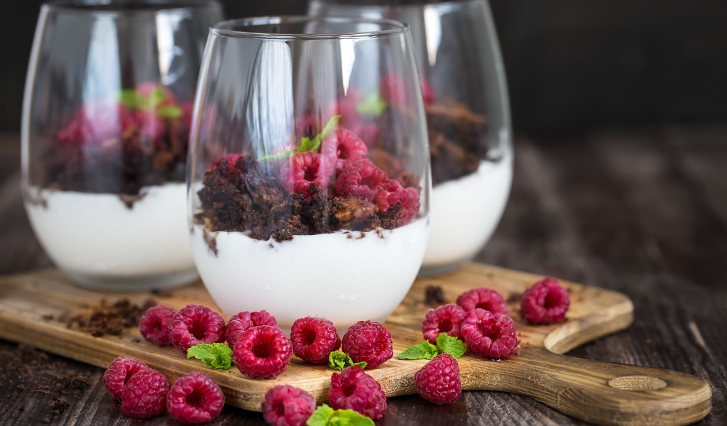Десерт со сливками, шоколадом и свежей малиной в стеклянных стаканах