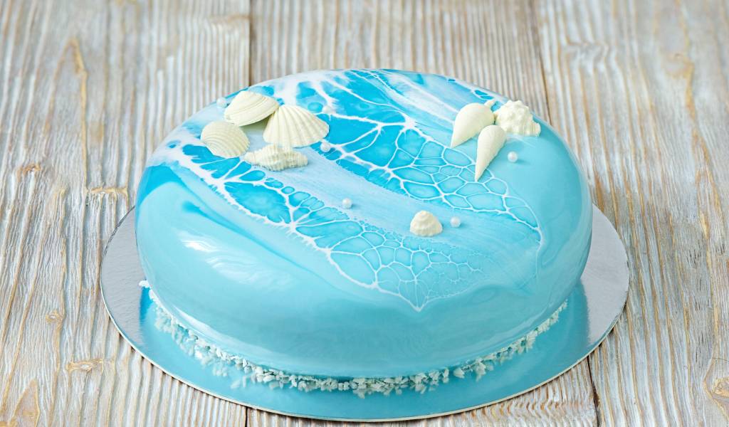 Глянцевый торт голубого цвета украшен сахарными ракушками