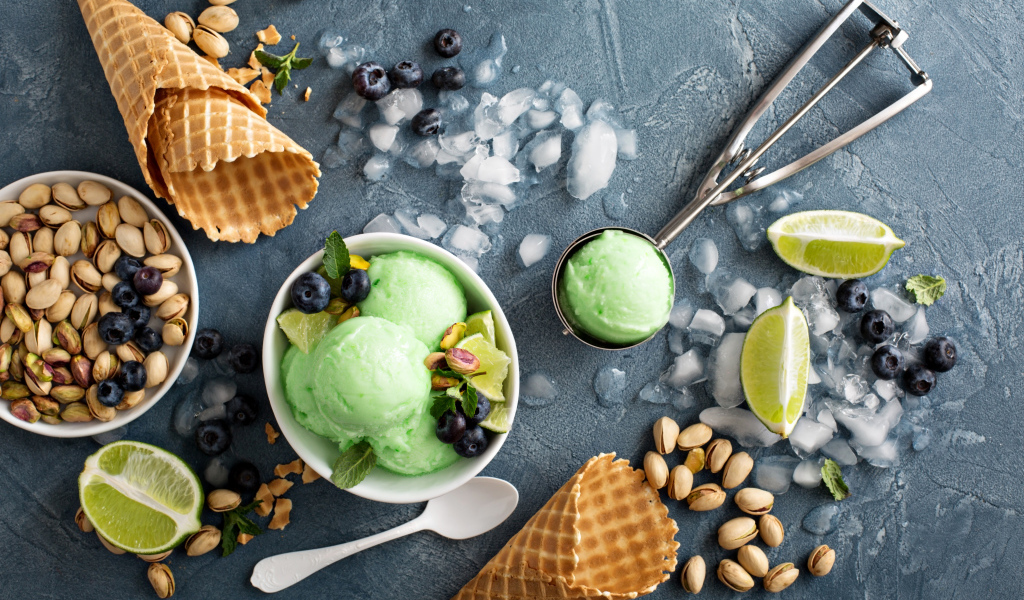 Мороженое с лаймом и фисташками на столе с вафельными рожками и льдом