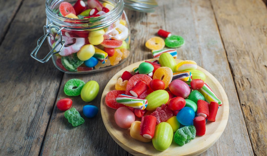 Разноцветные мармеладные конфеты в стеклянной банке на столе