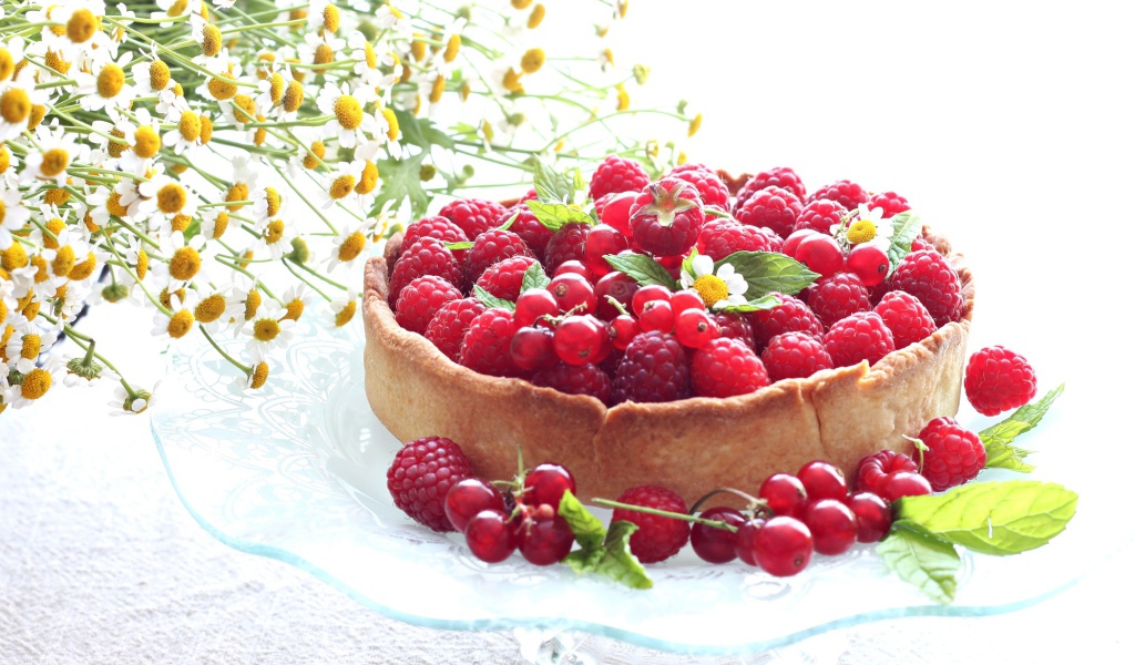 Пирог с ягодами малины и смородины на столе с ромашками