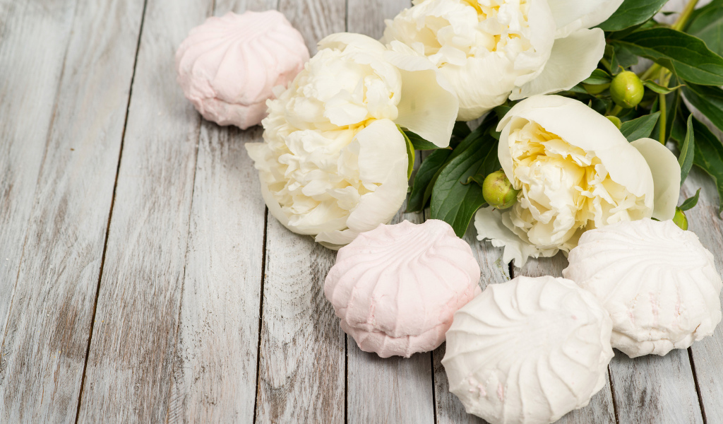 Сладкий зефир на столе с белыми пионами