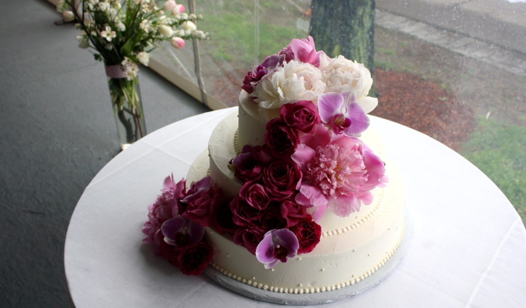 Большой свадебный торт украшен живыми цветами