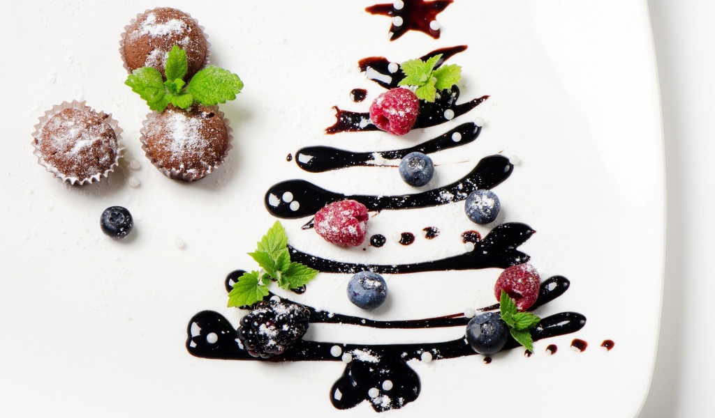 Три кекса и нарисованная шоколадом елка на белой тарелке