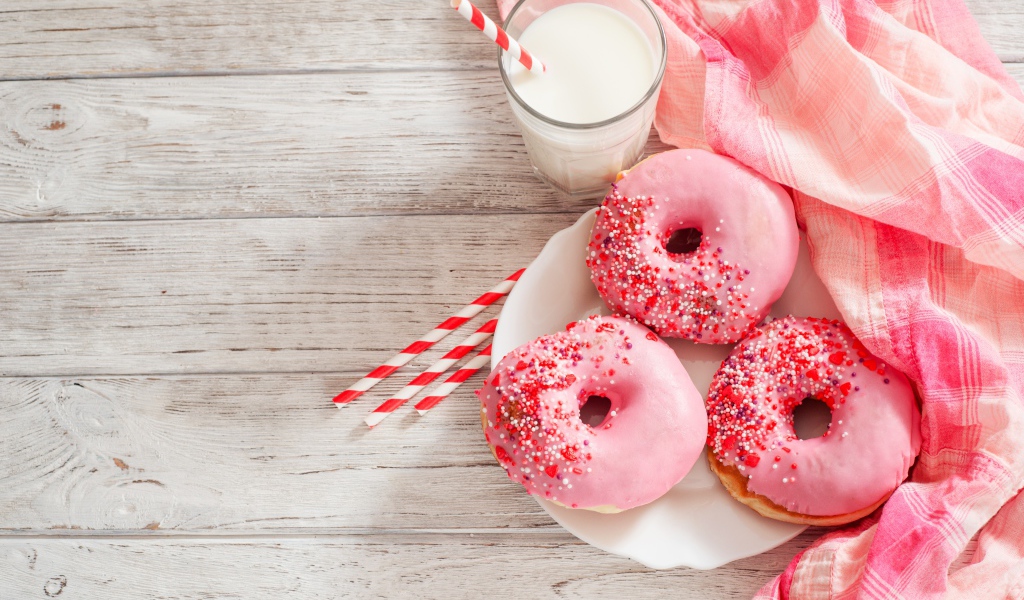 Три аппетитных пончика с розовой сахарной слазурью и стаканом молока
