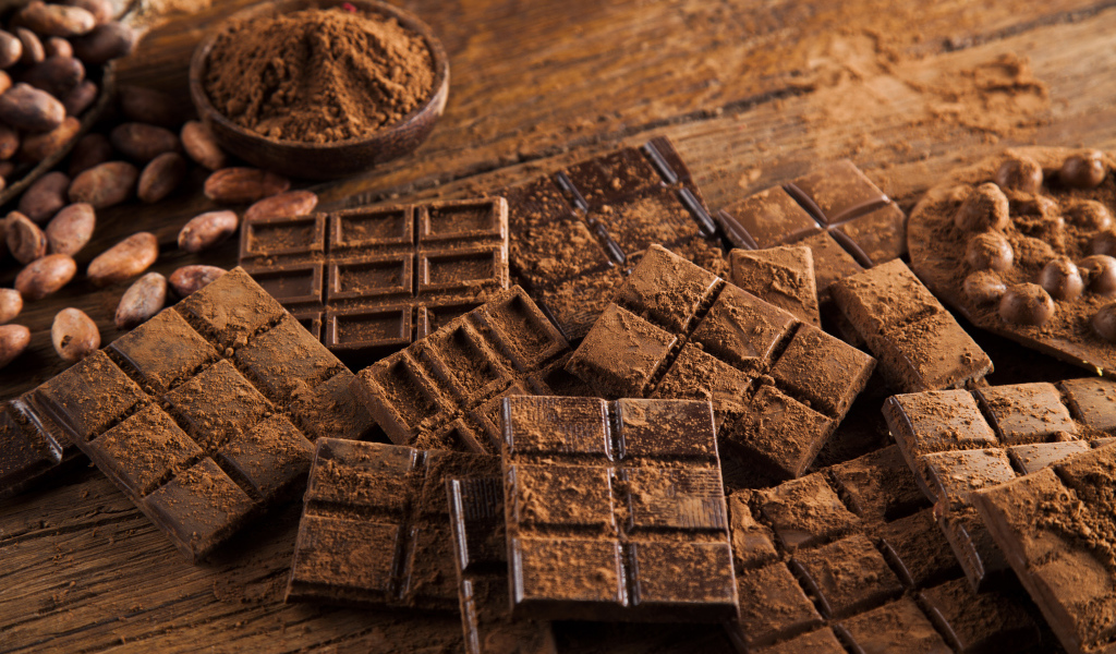 Плитки черного шоколада на столе с какао бобами