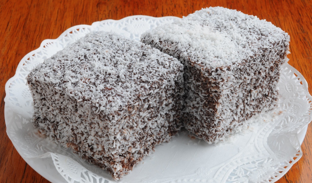 Два кусочка пирожного в кокосовой стружке на белой тарелке