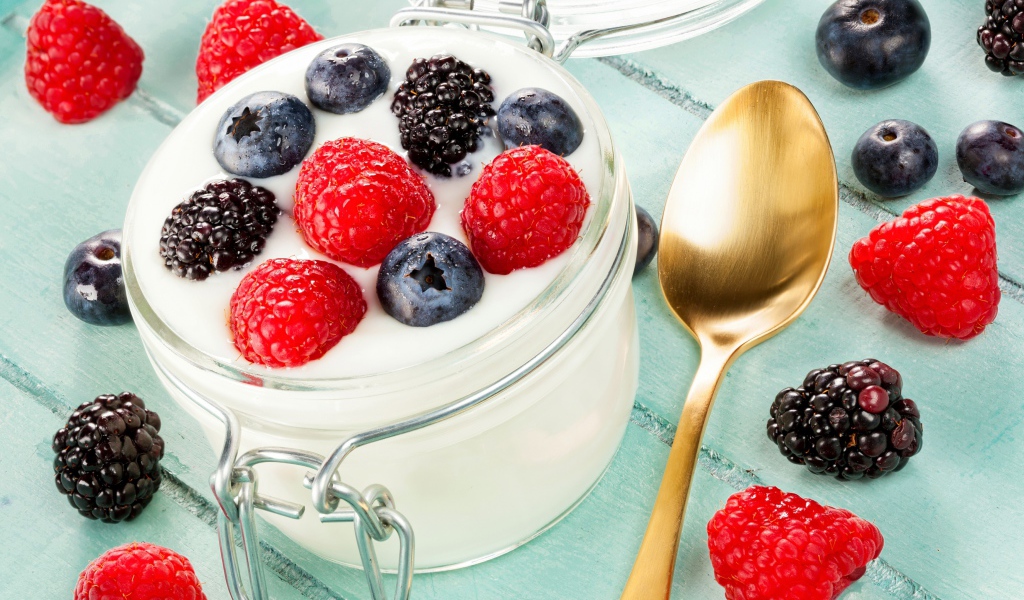 Йогурт со свежими ягодами малины, черники и ежевики в стеклянной банке на завтрак