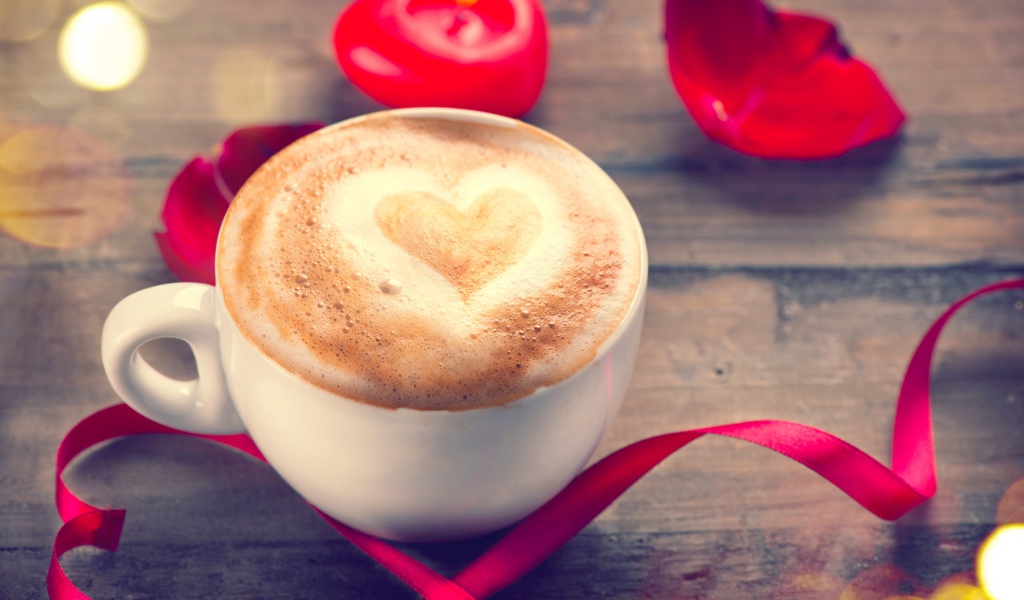 Чашка кофе на столе с красной свечой и лентой