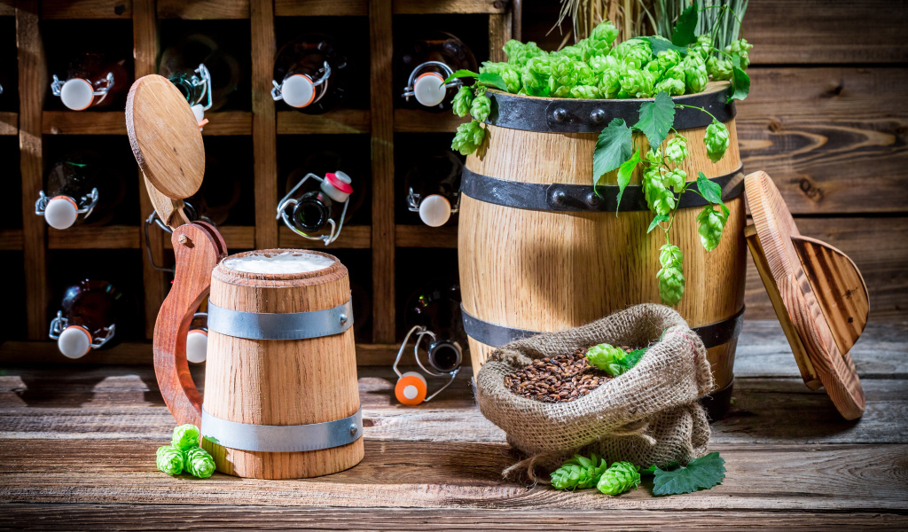 Бокал пива и деревянная бочка с хмелем на столе