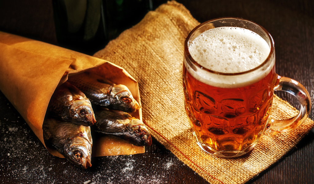 Бокал пива с сушеной рыбой на столе