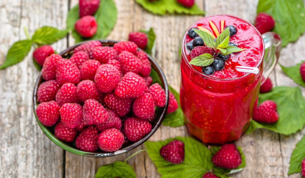 Стакан ягодного смузи на столе со свежими ягодами малины