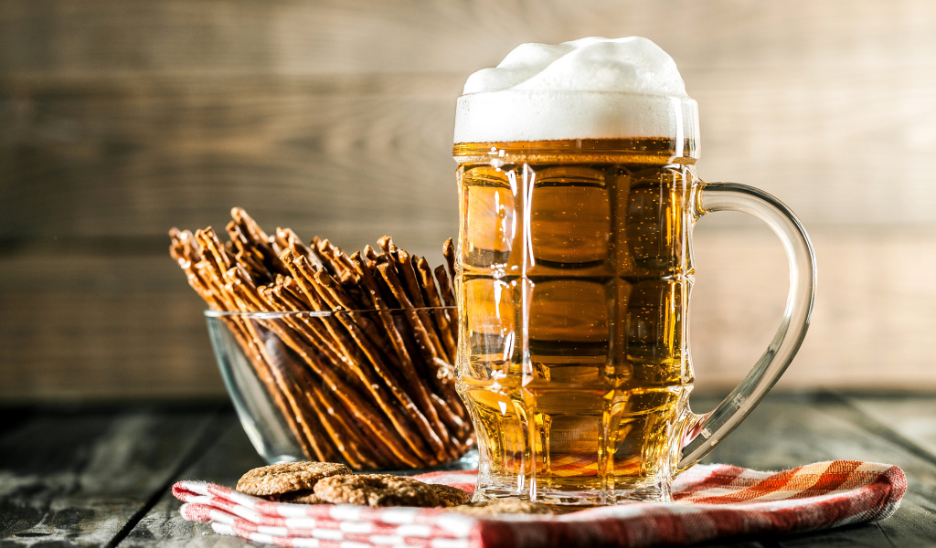 Бокал свежего пива с выпечкой на столе