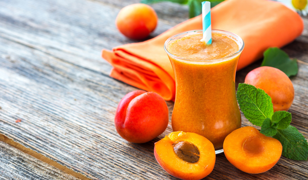 Абрикосовый смузи в стакане на столе со свежими ягодами