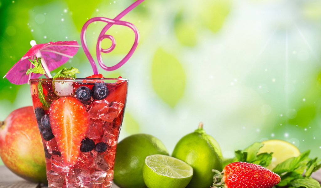 Коктейль с клубникой и ягодами черники в стакане со льдом на столе с лаймами и клубникой