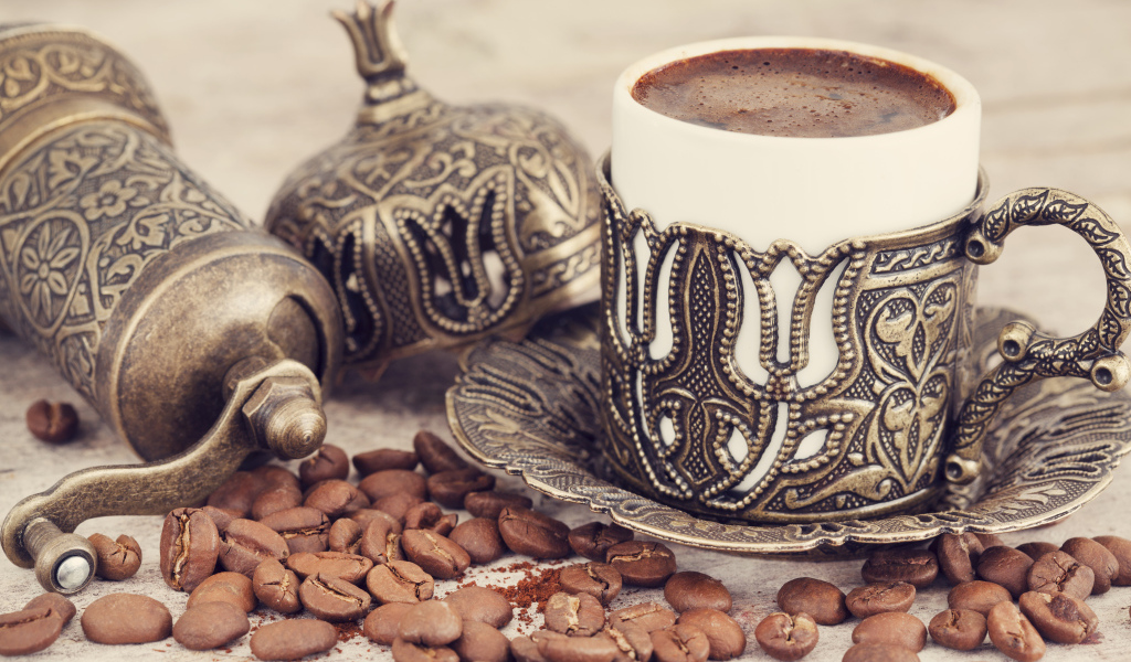 Вкусный кофе в красивой чашке с кофейными зернами на столе
