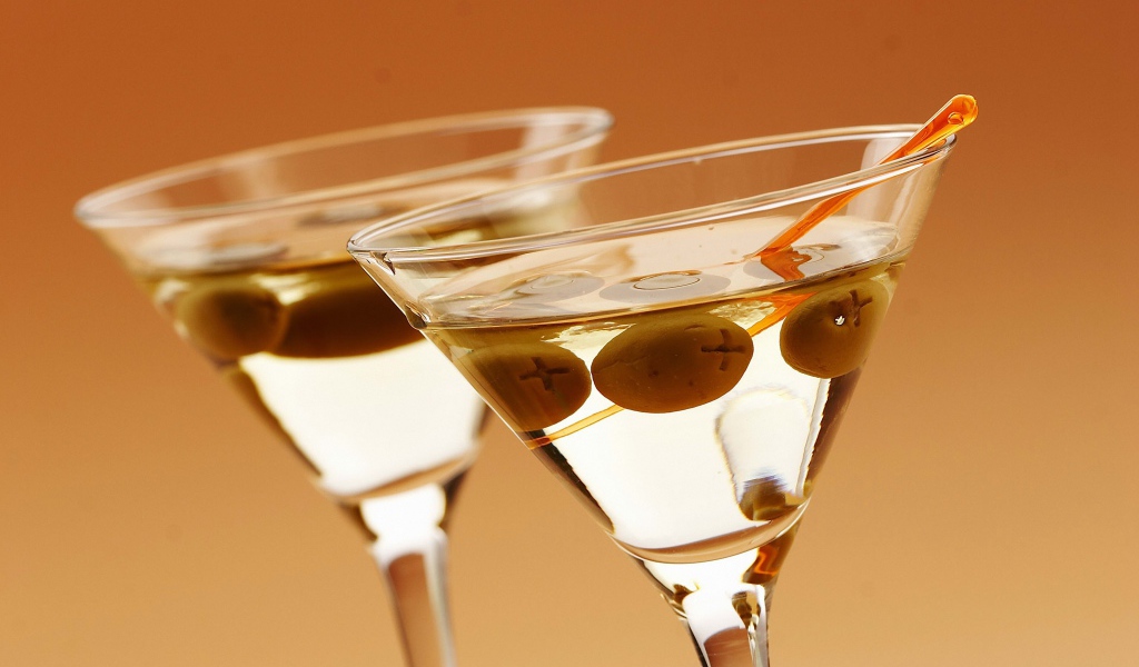 Напиток мартини в бокалах с оливками на кремовом фоне