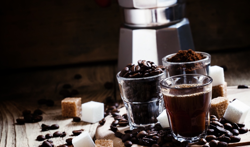 Стаканы с кофе, кофейными зернами и перемолотым кофе на столе с кубиками сахара