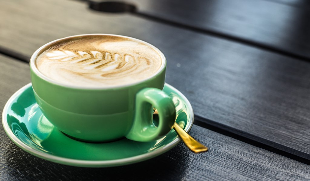 Зеленая чашка капучино с белой пенкой 