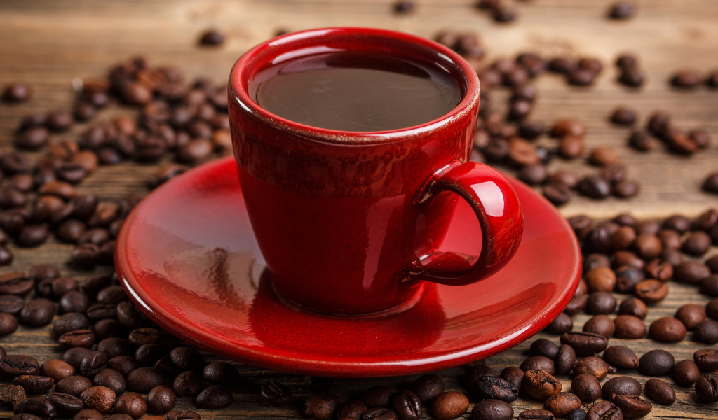 Красная чашка кофе на блюдце с кофейными зернами