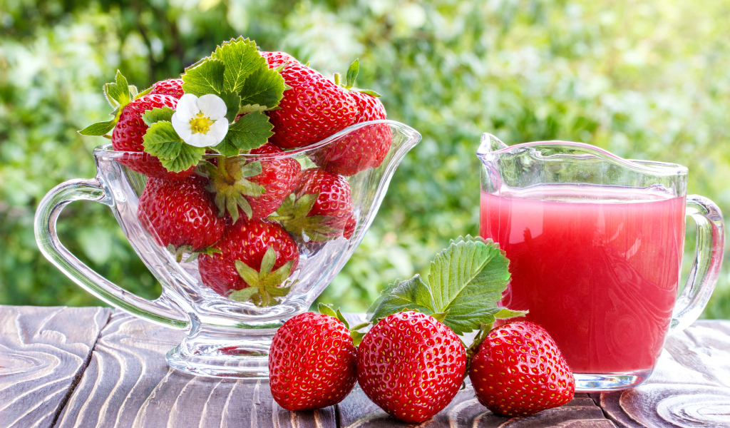 Клубничный сок в стеклянном графине на столе со свежей клубникой