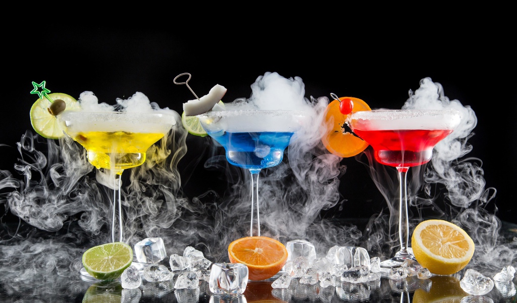 Три алкогольных коктейля с сухим льдом на черном фоне